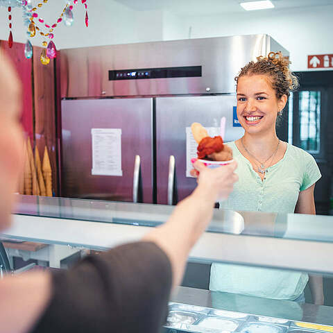 Eisverkäuferin gibt Gast ein Eis